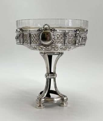 un plat ancien en argent surmonté d'un bol en verre