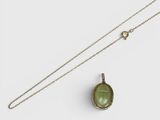 a green tourmaline pendant with a chain on a white background