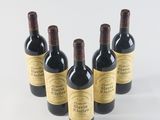 six bottles of wine are lined up in a row on a white surface