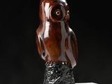 sculpture of an owl sitting on a tree stump on a black background