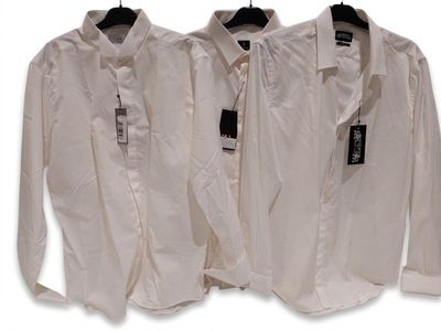 trois chemises blanches suspendues à un cintre sur un fond blanc