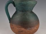 a green and brown pitcher sitting on a white surface