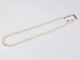 a close up of a pearl necklace on a white surface