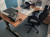 a desk with a phone, laptop, and other office supplies on it