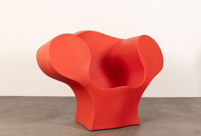 an orange chair sitting on top of a cement floor next to a white wall