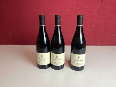 trois bouteilles de vin rouge sont posées sur une table devant un mur rouge