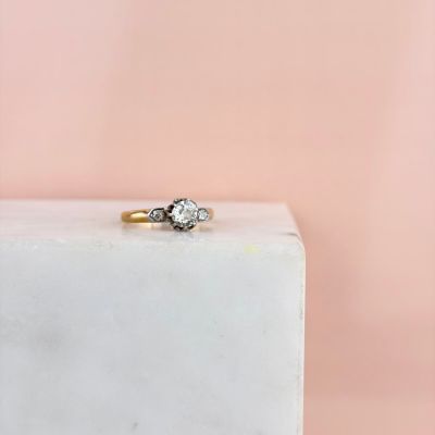 an engagement ring with two diamonds on top of a white marble block