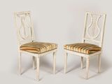 une paire de chaises peintes en blanc avec des coussins rembourrés à rayures