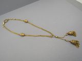 a close up of a gold necklace with tassels on a table