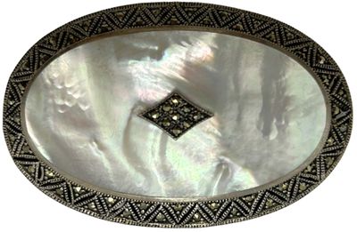 an oval mother of pearl tray with a diamond in the center