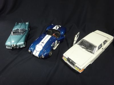 three toy cars sitting next to each other on a black surface