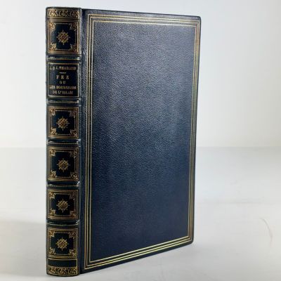 un livre bleu aux bords dorés, avec une couverture noire sur fond blanc
