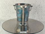 a silver ice bucket on a glass plate on a table