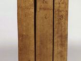 three old books sitting on top of each other on a white surface
