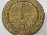 a close up of a gold plate with a picture of the eiffel tower