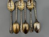 six spoons are lined up in a row on a gray surface