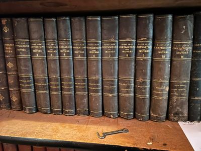 de nombreux livres anciens sur une étagère sur laquelle se trouve une paire de ciseaux
