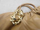 a tan purse with a gold chain hanging from it