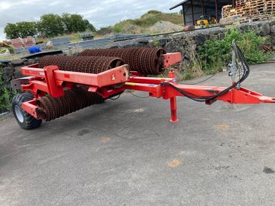 une photo d'une remorque rouge sur laquelle est chargé un gros rouleau de foin