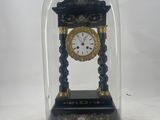 a small clock under a glass dome on a table