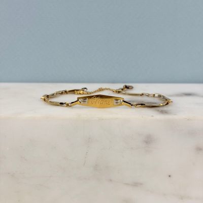un gros plan d'un bracelet en or posé sur une surface en marbre