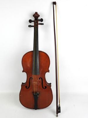 un vieux violon avec un archet et un repose-archet posé sur une surface blanche