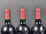 three bottles of red wine are lined up on a table