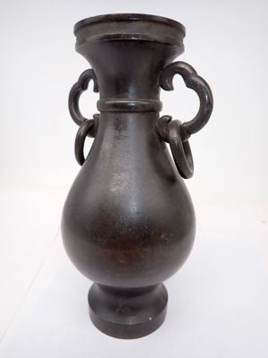 un vase noir posé sur une surface blanche