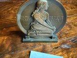 a silver medal on a wooden table with a sticker next to it