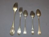 four silver spoons and a fork are lined up on a table