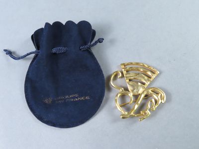une image représentant une pochette en velours bleu ornée d'une broche en or et d'une broche en or