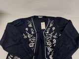 une veste noire ornée de fleurs blanches, posée sur une table