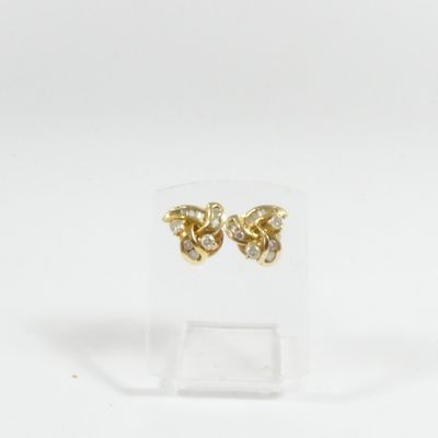 une paire de boucles d'oreilles en or et diamants posée sur un présentoir transparent