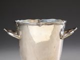 an antique silver plated ice bucket with handles on a gray surface