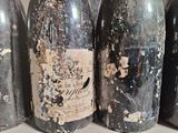 several old bottles of wine are lined up on a shelf
