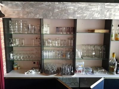 des bouteilles et des verres posés sur une étagère dans une pièce où se trouve un rideau rouge