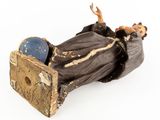 figurine of a man laying on a chair with a hat on his head