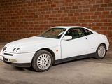 a white car that is parked in front of a brick wall