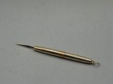 an image of a gold colored pen sitting on top of a white surface