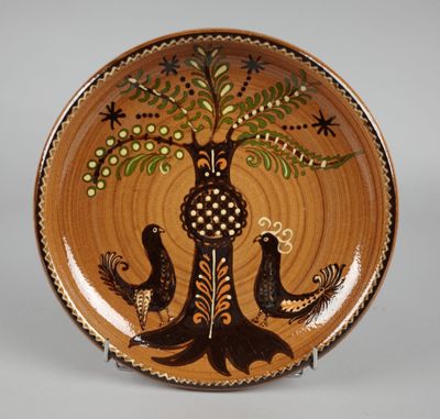 une assiette marron décorée d'oiseaux et d'un arbre