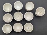 six white bowls are arranged in a circle on a black surface