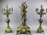 three candlesticks and a clock with a statue on top of them