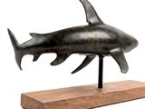 statue of a shark on a wooden base on a white background