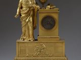 une image représentant une horloge en or avec la statue d'un homme tenant un globe terrestre