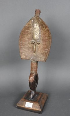 statue représentant un oiseau tenant une feuille, posée sur un socle en bois