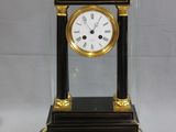 une horloge noire et dorée surmontée d'un dôme en verre