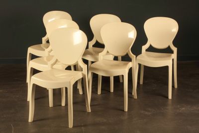 four white plastic chairs sitting in a row against a black wall