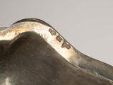 a silver sculpture of a shell on a white surface