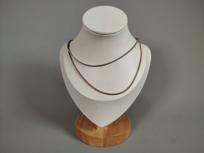 a white mannequin on a wooden stand with a necklace on it