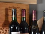 several bottles of wine are lined up on a shelf in front of a wooden box